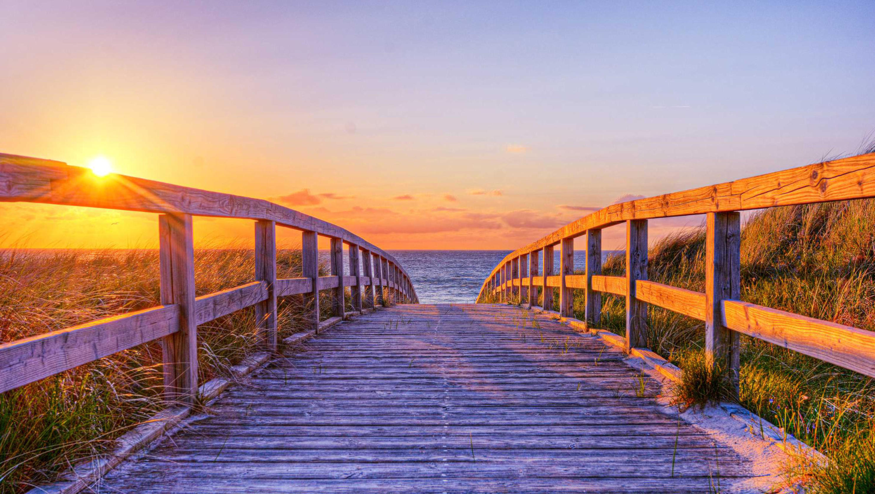 Holzsteg durch die Dünen zum Meer bei Sonnenuntergang