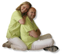 Gloria und Olaf Preuss sitzen in grünen Poloshirts nebeneinander und umarmen sich
