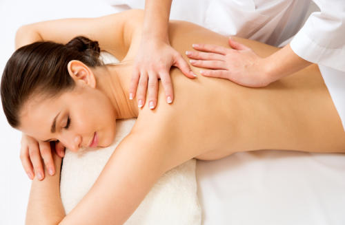 Frau liegt mit geschlossenen Augen auf der Massageliege und erhält eine Rückenmassage