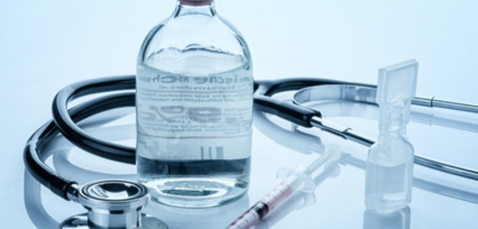 Infusionsflasche, Stethoskop, Spritze und Ampulle auf einer spiegelnden Fläche